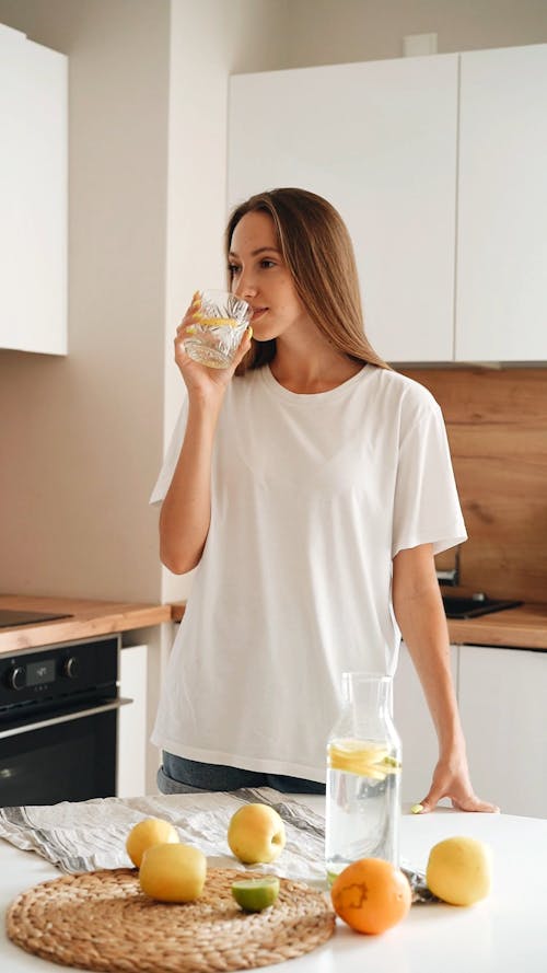 A Woman Drinking a Glass of Water with Lemon