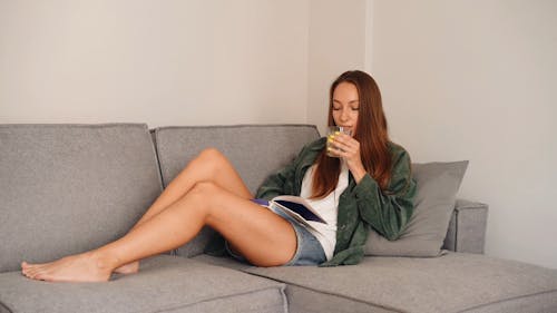 A Woman Reading a Book while Drinking Water with Lemon