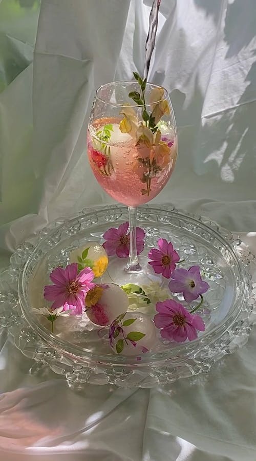 Water being Poured in a Glass with Flowers