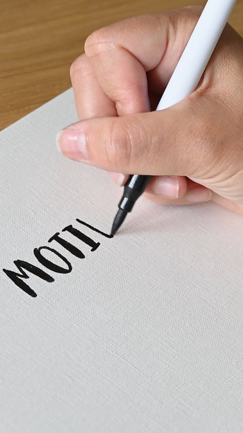 A Person Writing Motivation on a White Paper