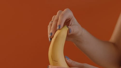 A Close up of a Person Peeling and Squeezing a Banana
