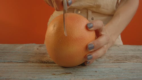 A Person Slicing a Grapefruit Into Half