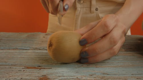 A Person Holding a Kiwi and a Knife