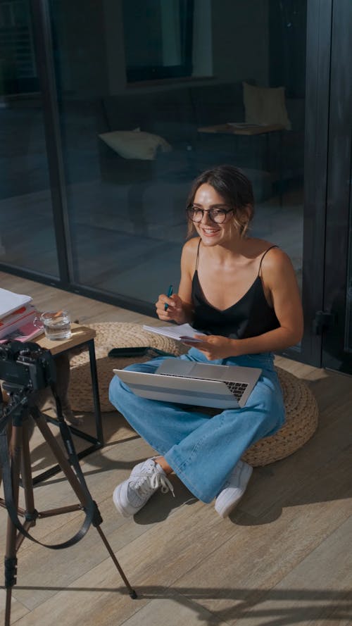 A Woman Recording a Video while Sitting on a Floor Cushion