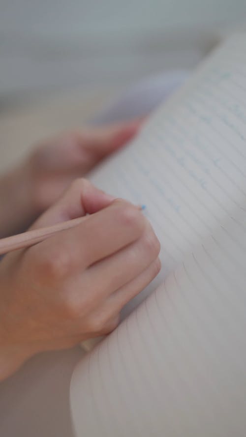 A Person Writing on a Page in a Notebook