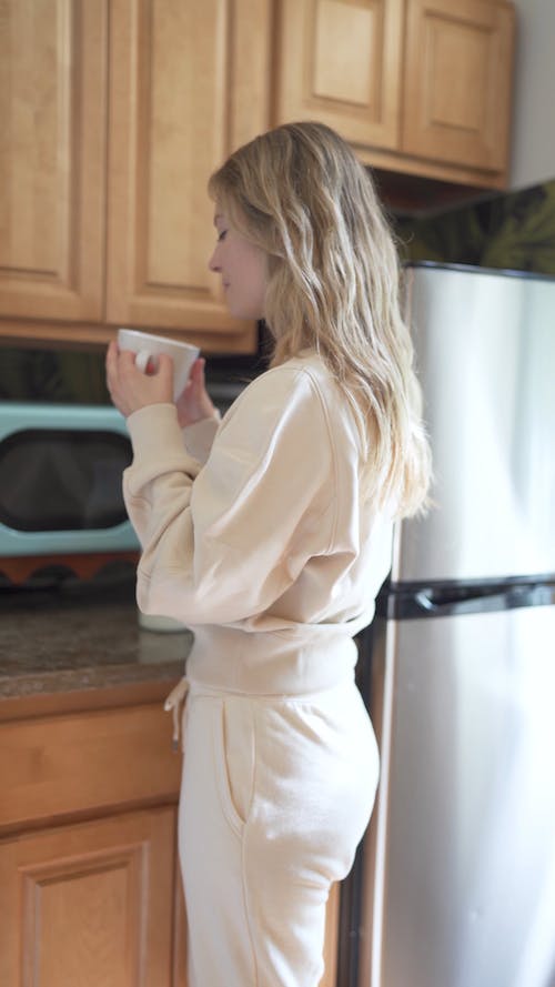 A Woman Looking at a Coffee Cup in a Kitchen