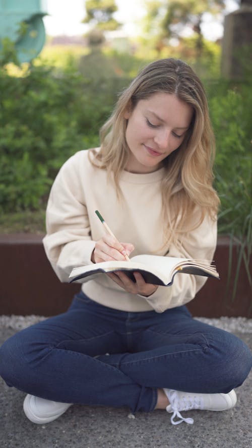 Woman Writing on a Notebook While Sitting on the Floor