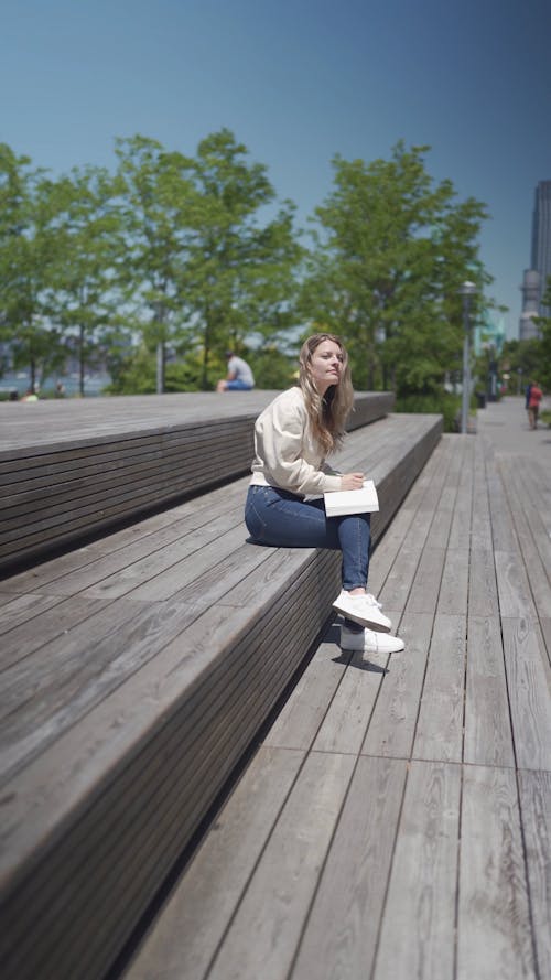 Woman Sitting on Bench While Writing on Notebook