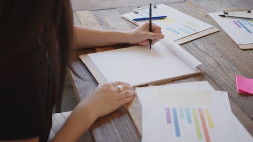 A Female Person Writing on Paper