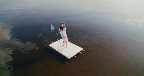 A Woman Holding a White Flag While Standing on a Raft