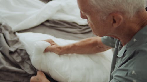 An Elderly Man Placing a Pillow inside a Pillowcase