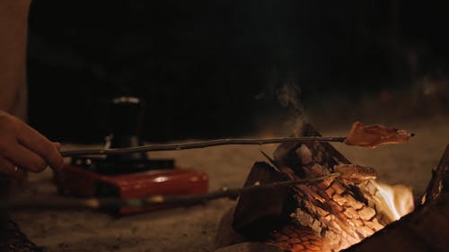 People Cooking Meat on a Bonfire