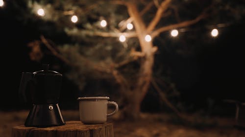 Coffee Pot and a Cup on a Wood Log