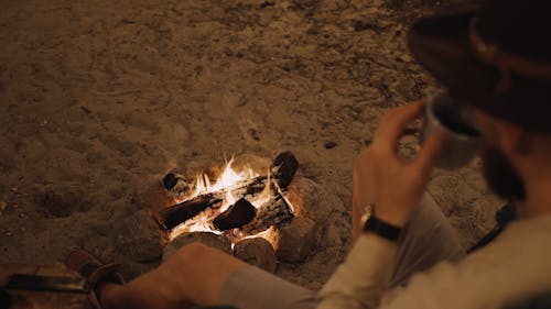 A Man Drinking Coffee Near Bonfire