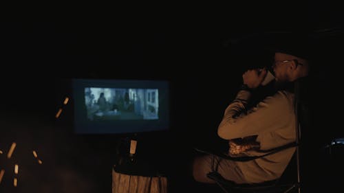 A Man Drinking Coffee and Watching a Movie Outdoors