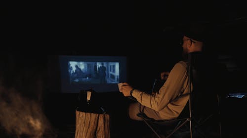 A Man Watching a Movie at a Camping Site