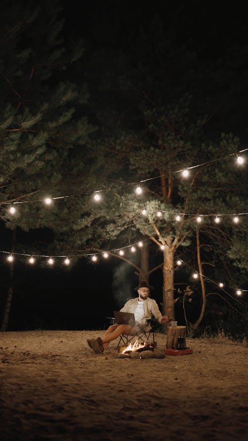 Tired Man Sitting Near a Campfire