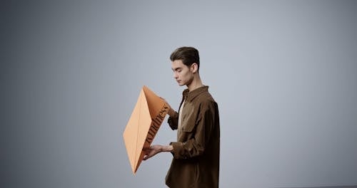 A Man Looking at the Big Paper Plane He is Holding