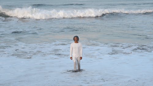 A Man Wearing a Fish Bowl on his Head Walking at a Beach