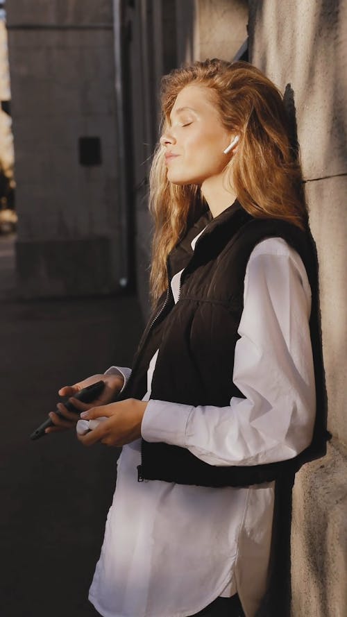 A Woman using Smartphone and Airpods while Listening to Music