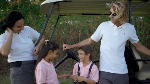 A Couple Standing beside a Golf Cart with their Daughters