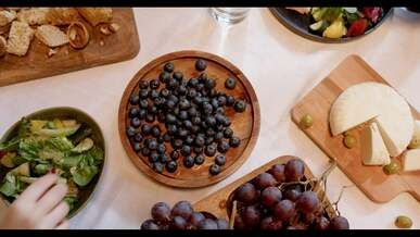 close up footage of people getting blueberries on a wooden plate