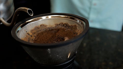 A Person Pouring a Hot Water on a Coffee