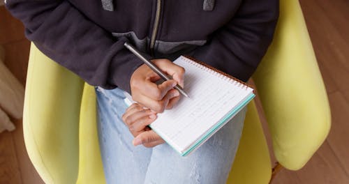 Person Writing on a Notebook