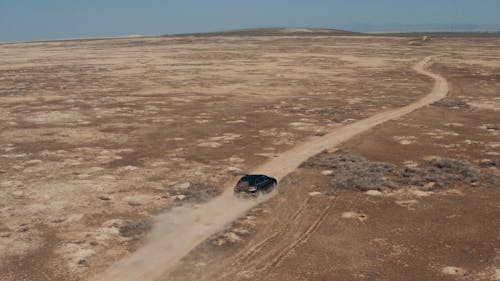 A Car Driving on a Remote Dirt Road 