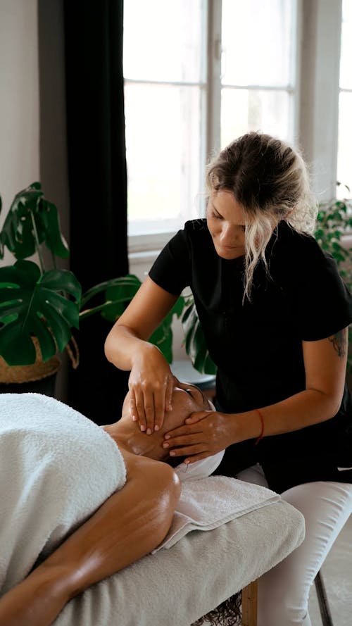 A Woman Massaging a Face of Her Client