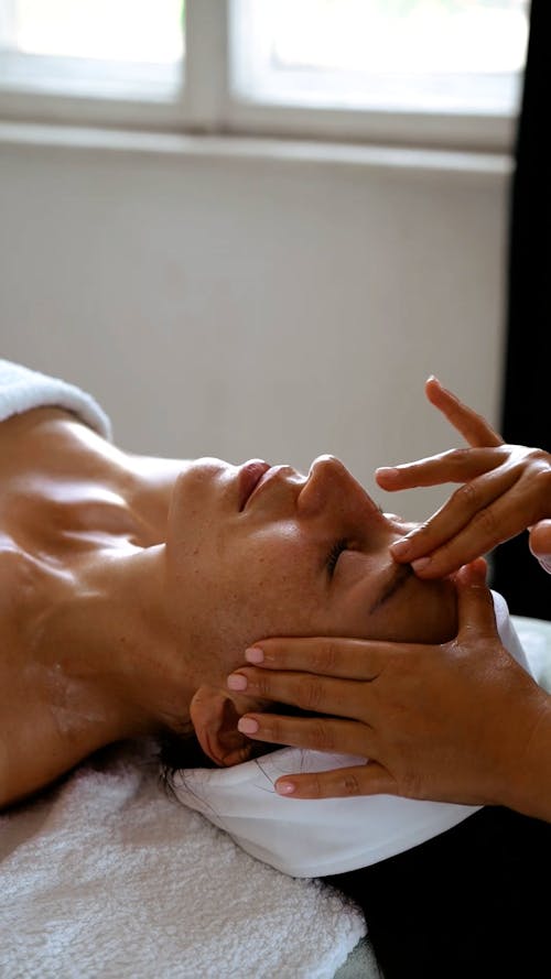 A Woman Relaxing by Having Her Face Massaged