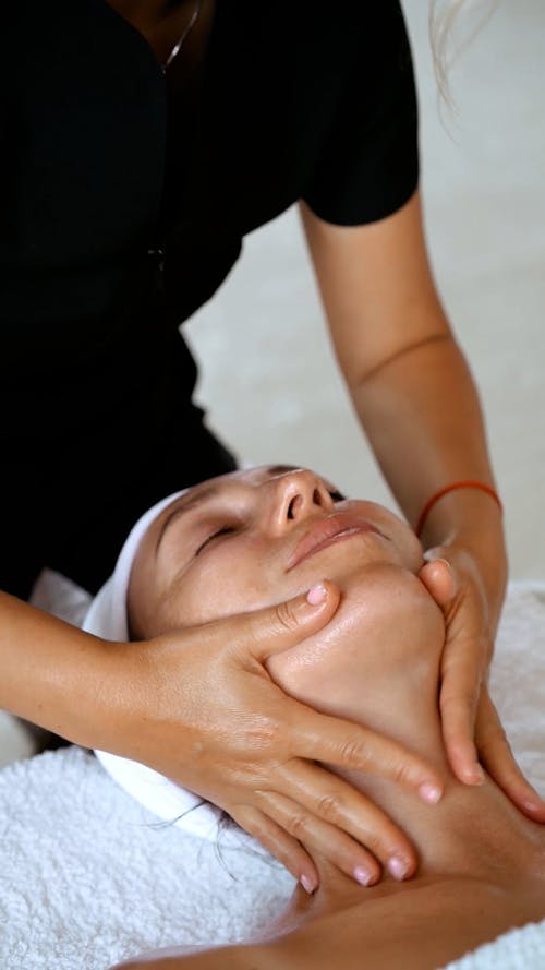 Person Massaging the Face of a Woman
