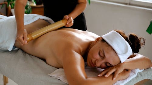A Therapist Using a Rolling Pin in Massaging a Client's Back