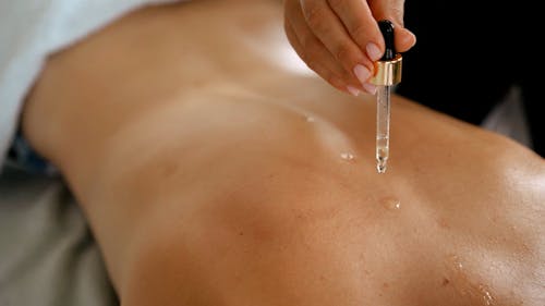 A Massage Therapist Putting Essential Oil on a Client's Back