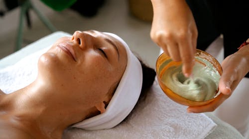 A Person Applying Facial Mask on a Client