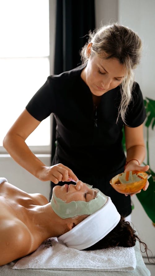 A Woman Applying a Face Mask while Talking to Her Client