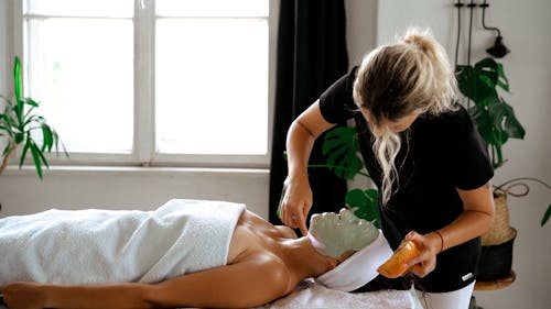 A Woman Applying a Face Mask on Her Client's Face