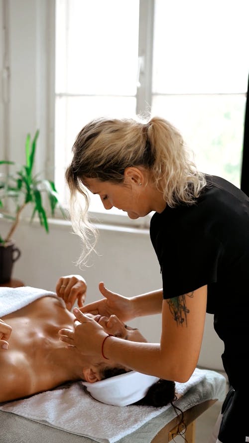 A Woman Massaging the Client's Face