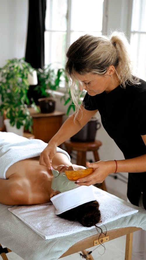 A Woman Applying a Face Mask on her Client's Face