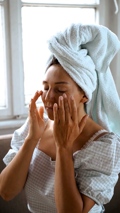 Woman Putting On Facial Care While Eyes Closed
