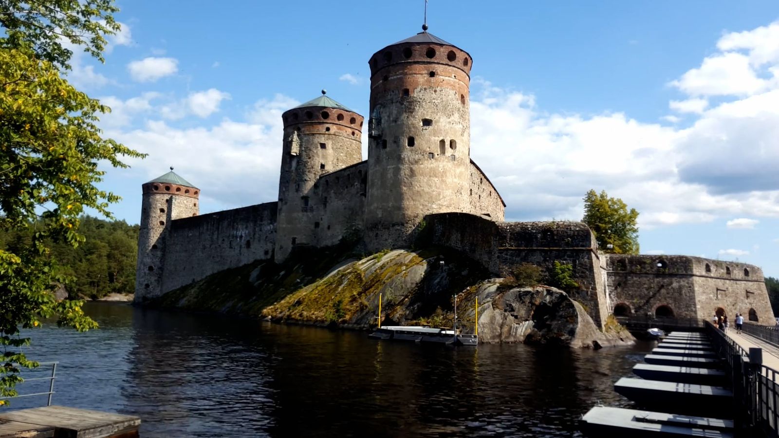 a girl walks along the bridge in front of an ancient red brick castle ...