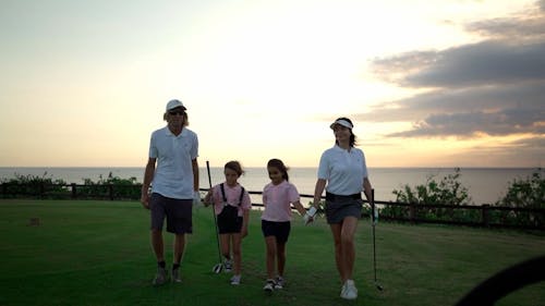 A Golfer Couple Walking towards a Golf Cart with their Daughters