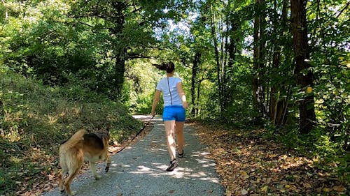 A Woman Jumping while Walking with Her Dog