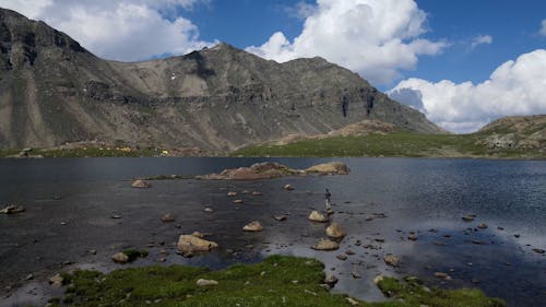 A Man Standing on a Rock in a Mountain Lake 