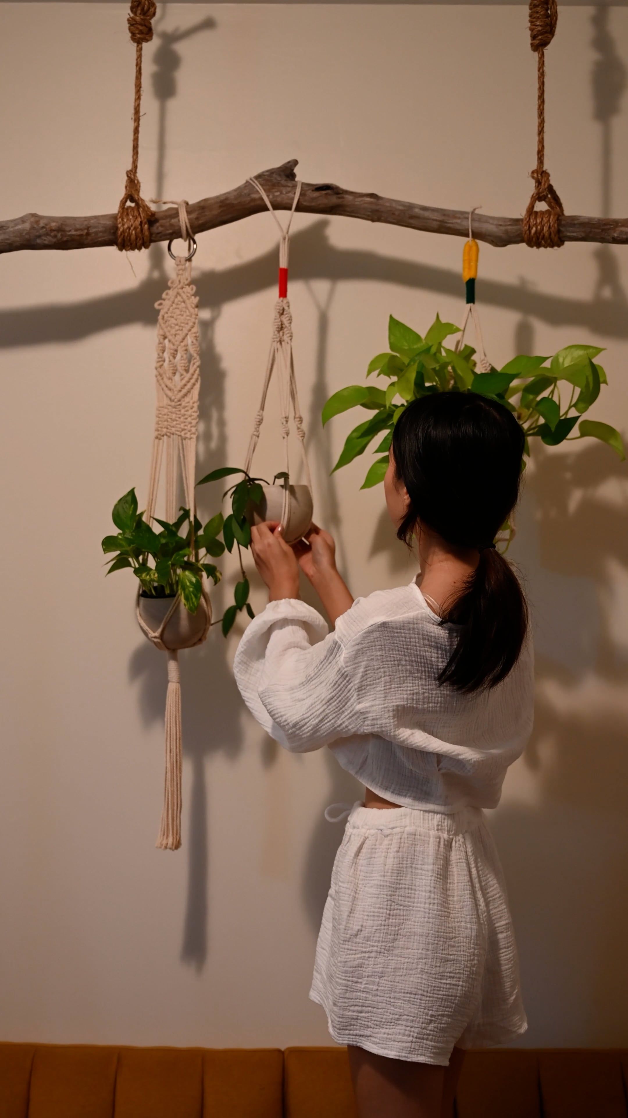 A woman in a white robe hanging plants from a wall Free Stock Video ...