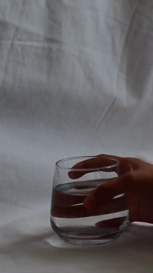 A Person Putting Roses in a Glass With Water 