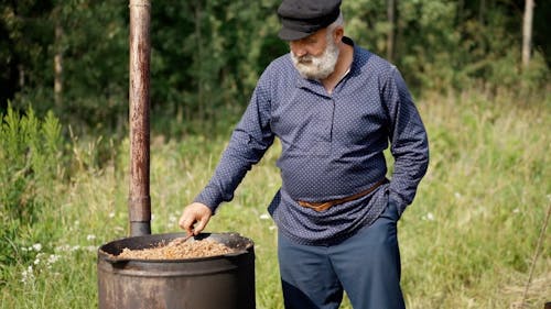 An Elderly Man Cooking Outdoors