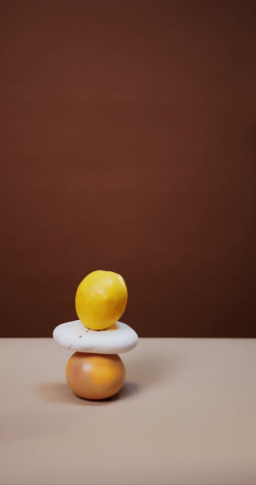 Stacked Fruits and a Stone Tipping over