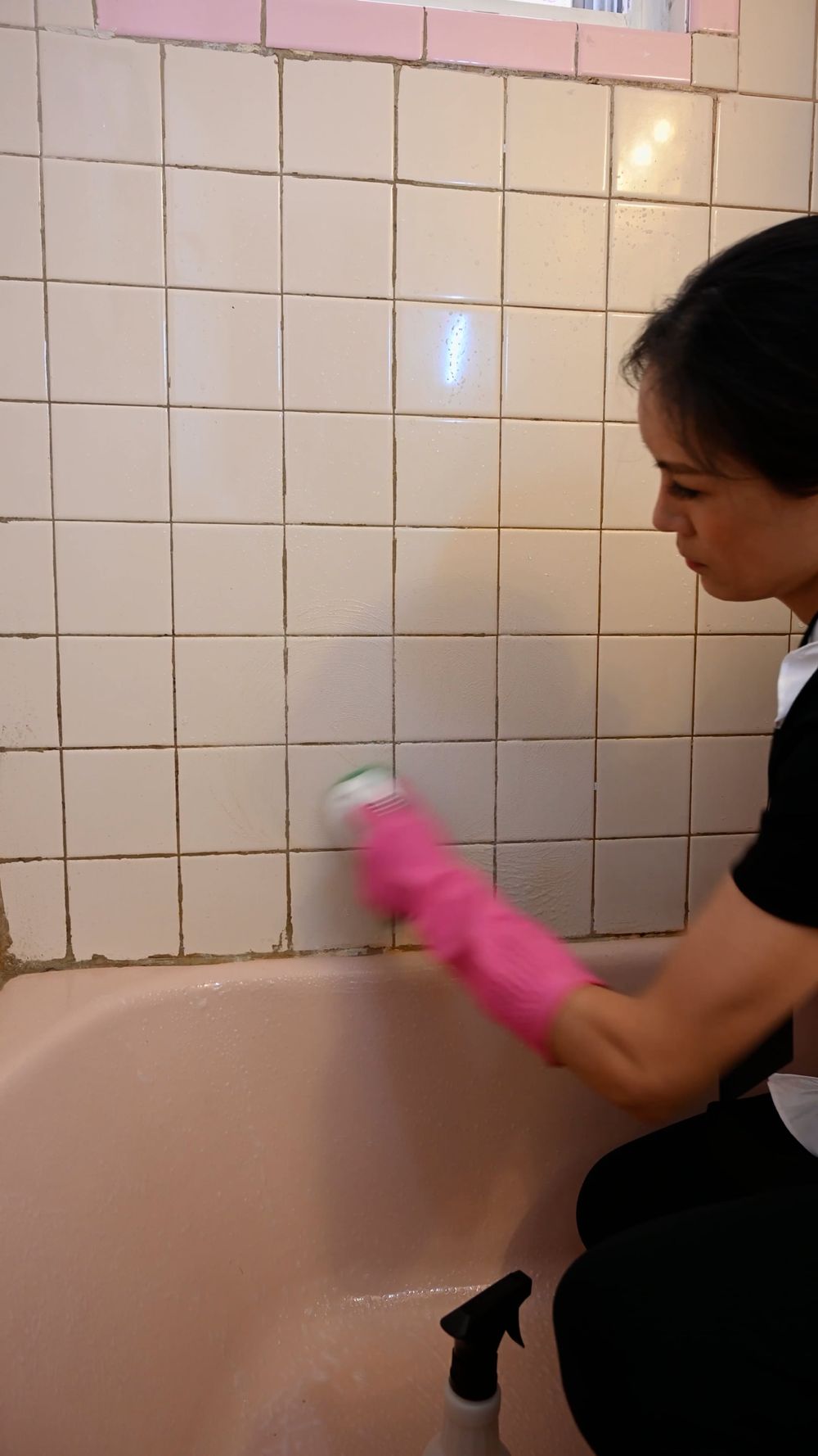 Housekeeper cleaning a bathtub with gloves