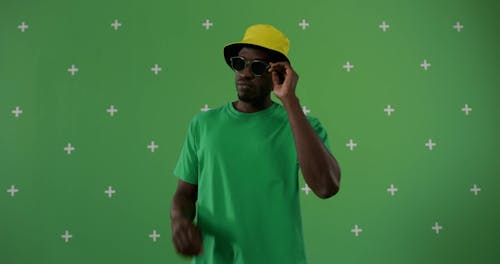 A Man Holding His Shades while Wearing a Yellow Bucket Hat